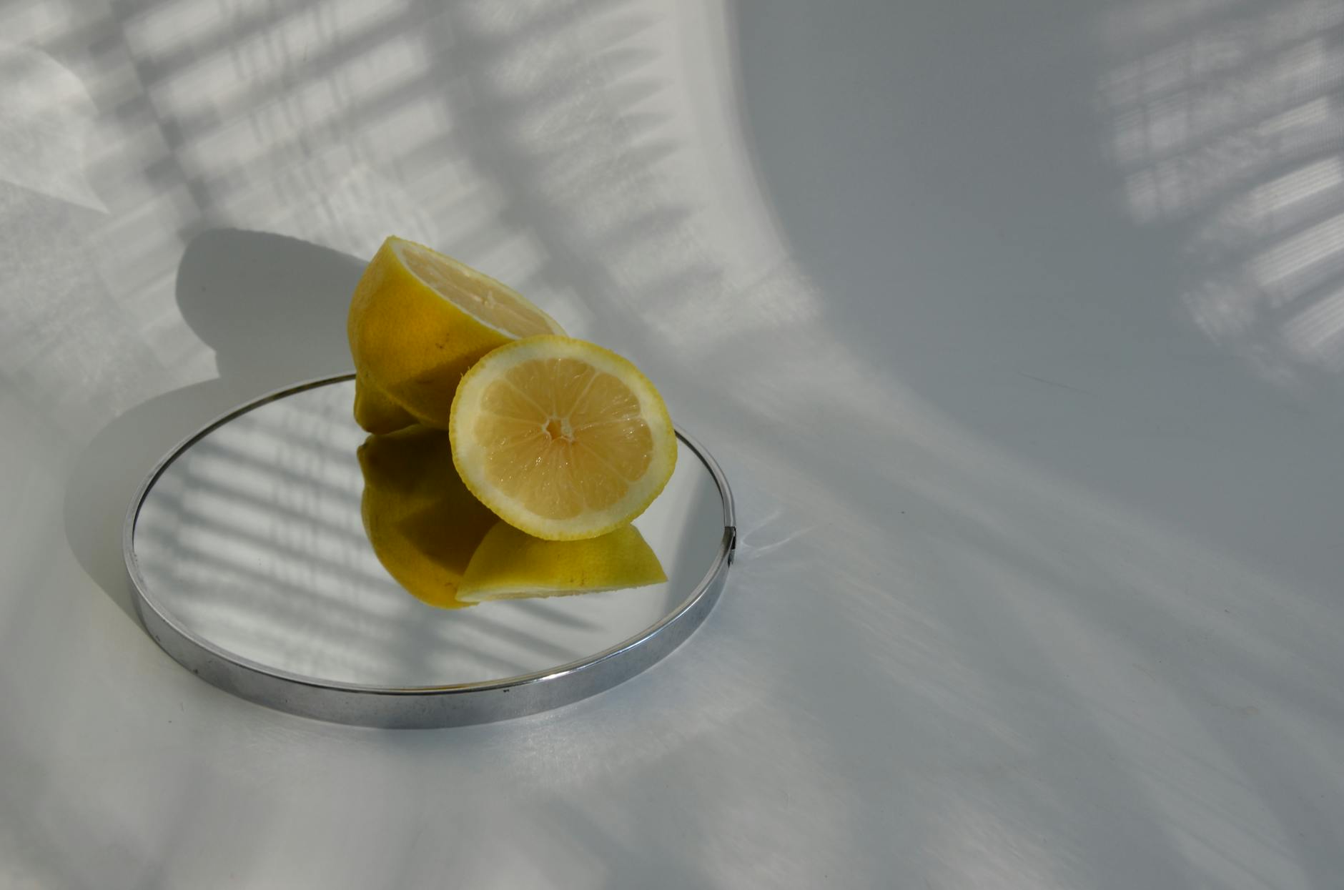 Sliced lemons on a mirror with soft shadows, representing fresh approaches to pleasure under stress