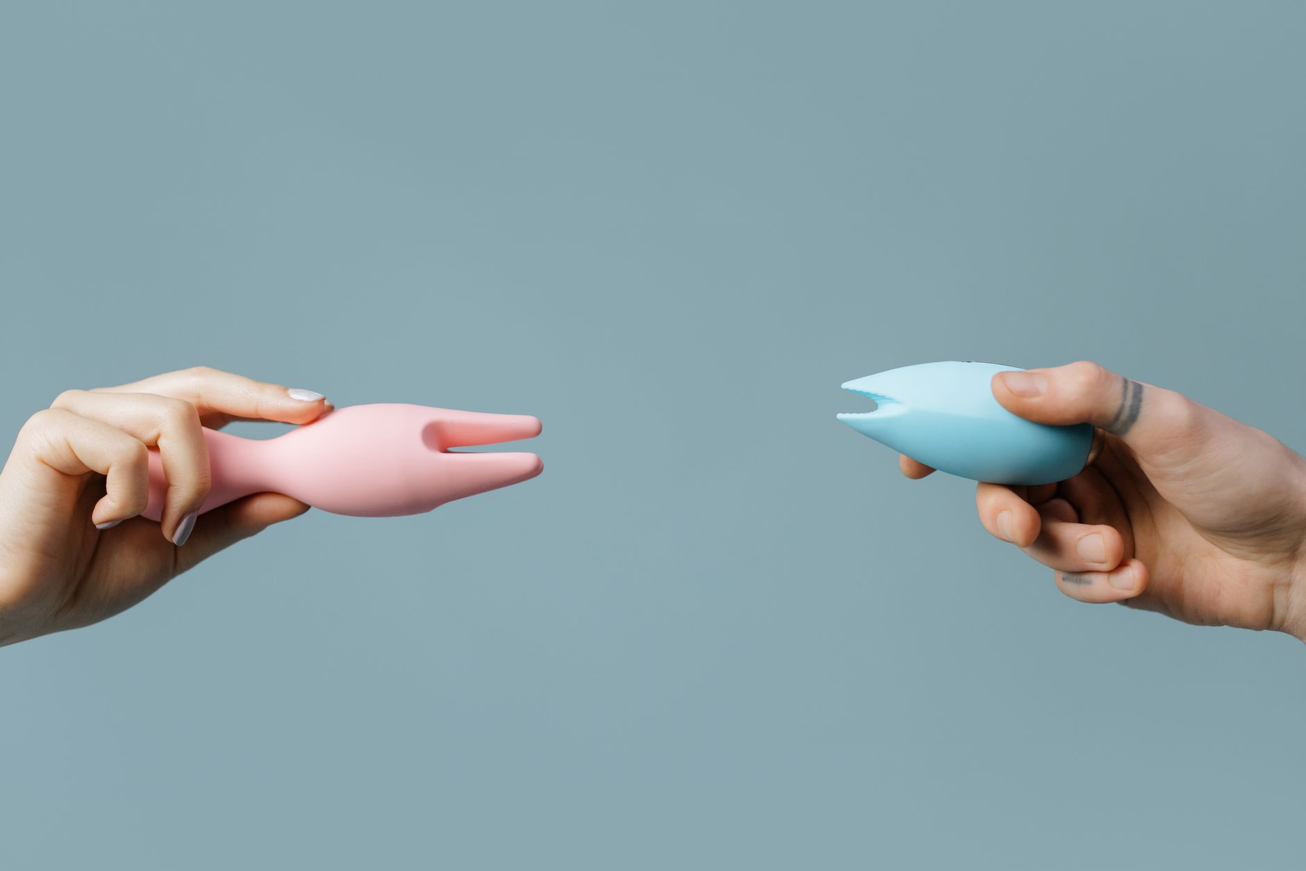 Hand holding a lemon on a soft pink background, symbolizing freshness and intimate pleasure