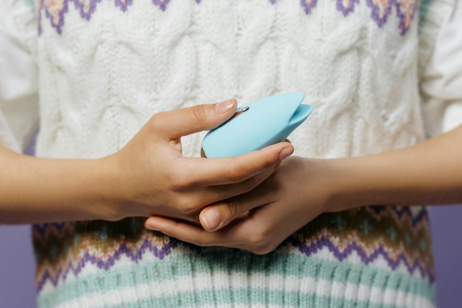 Woman holding pink and blue clitoral vibrators thoughtfully