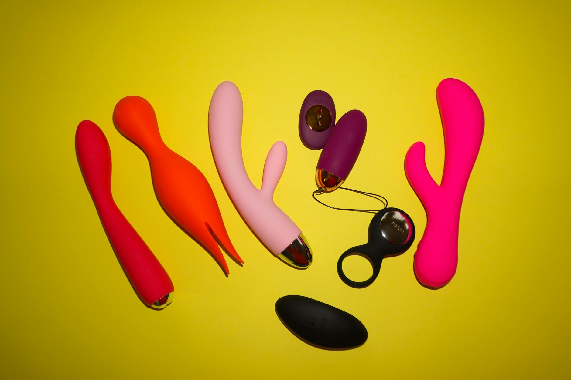 A woman holding a pink vibrator with art books in the background, emphasizing intimate personal choice