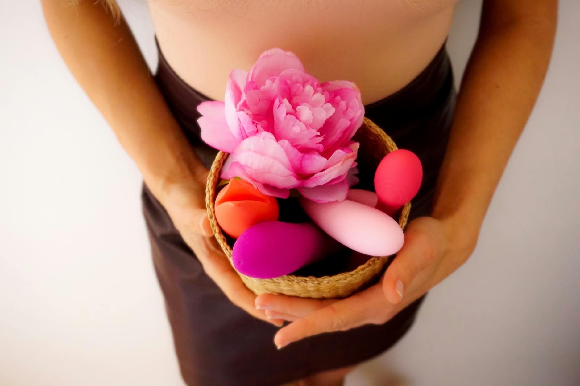 A blue vibrator surrounded by flowers and citrus on a bright yellow background, symbolizing pleasure and freshness
