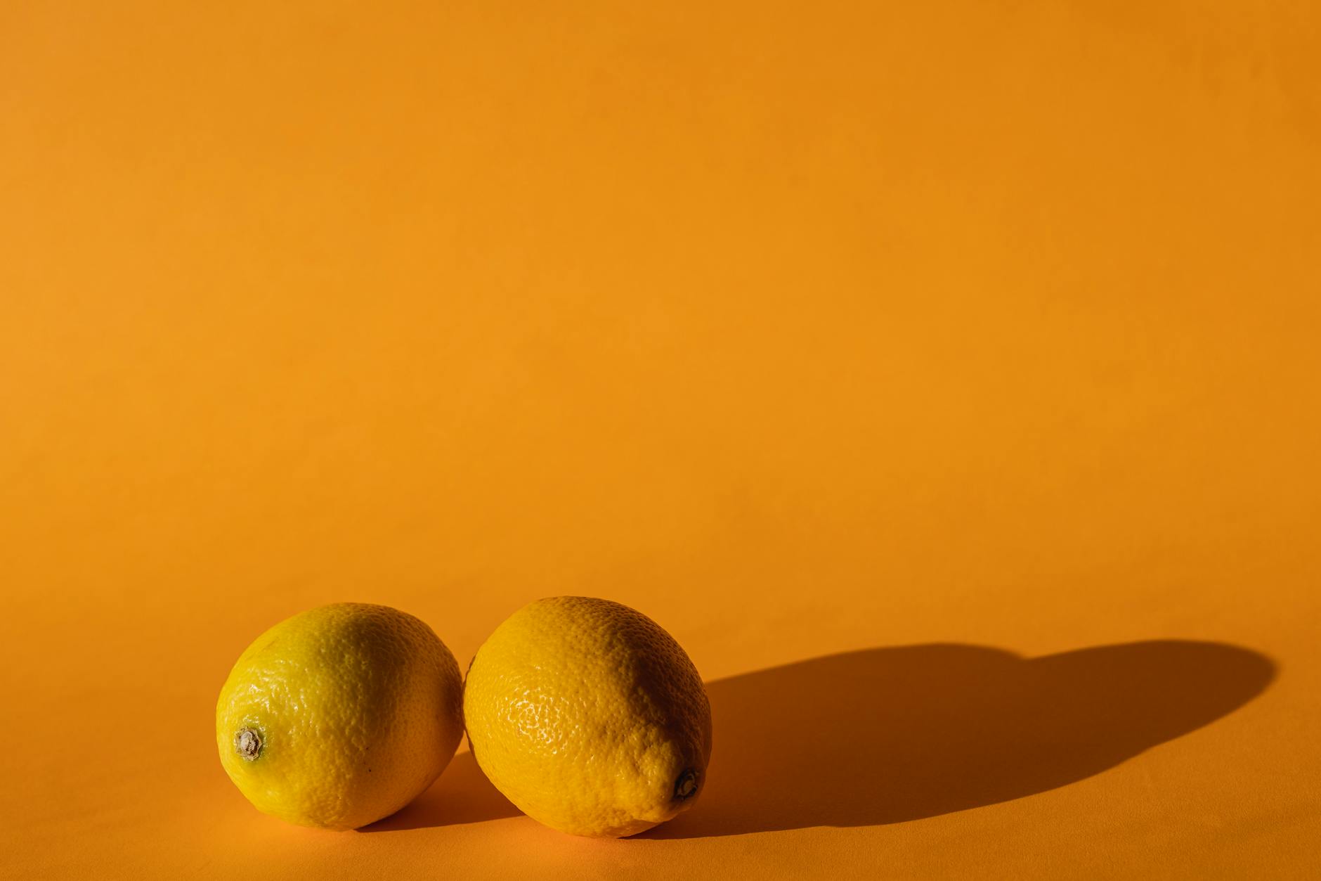 Fresh bright lemons arranged on a vibrant yellow background in natural daylight